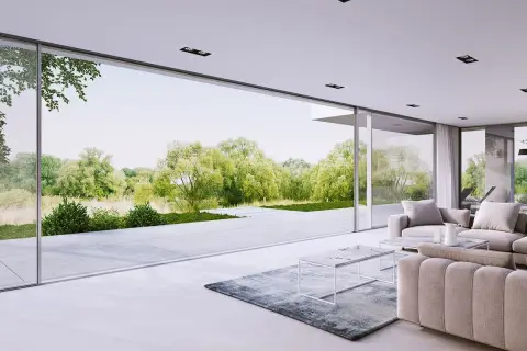 Nowoczesny salon z wygodnymi sofami i stolikami, przez ogromne okna panoramiczne widać bujną zieleń ogrodu.