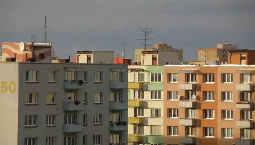 Widok na fasady bloków mieszkalnych w różnych kolorach, z balkonami i oknami.